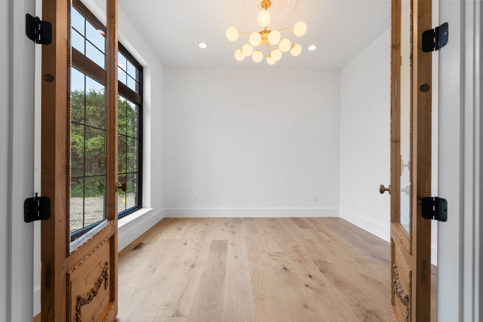 Arched entry doors opening to wide-plank oak flooring